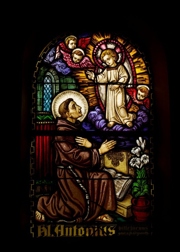 Colorful stained glass artwork depicting a religious scene with a saint and angels.